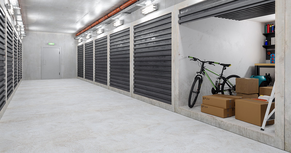 A storage facility hallway. A storage unit is open, and inside is a bicycle plus moving boxes.