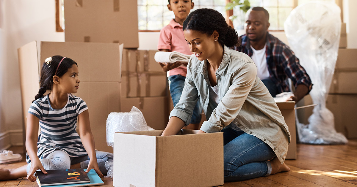 A family of four take items out of moving boxes. They have just retrieved them from their storage unit after their long distance move.