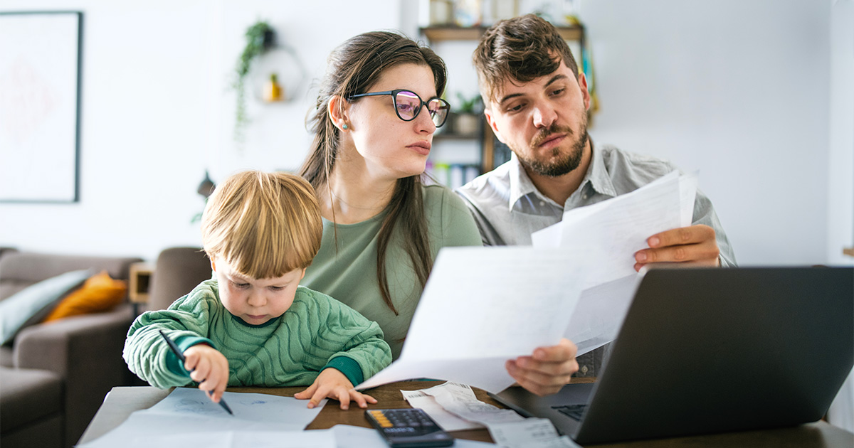 A couple sits with their child at a kitchen table looking over moving valuation paperwork for their long distance move.