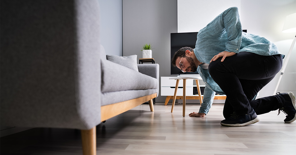 A man inspects his couch after a long distance move to make sure there isn't any damage. He is using moving valuation to protect his belongings.