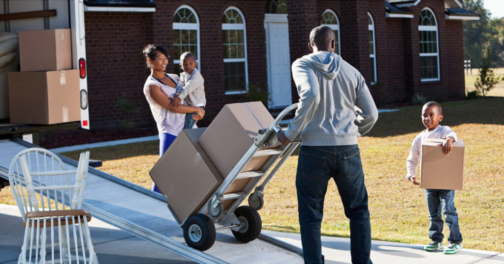 A family packs boxes and loads them onto a rental moving truck. 