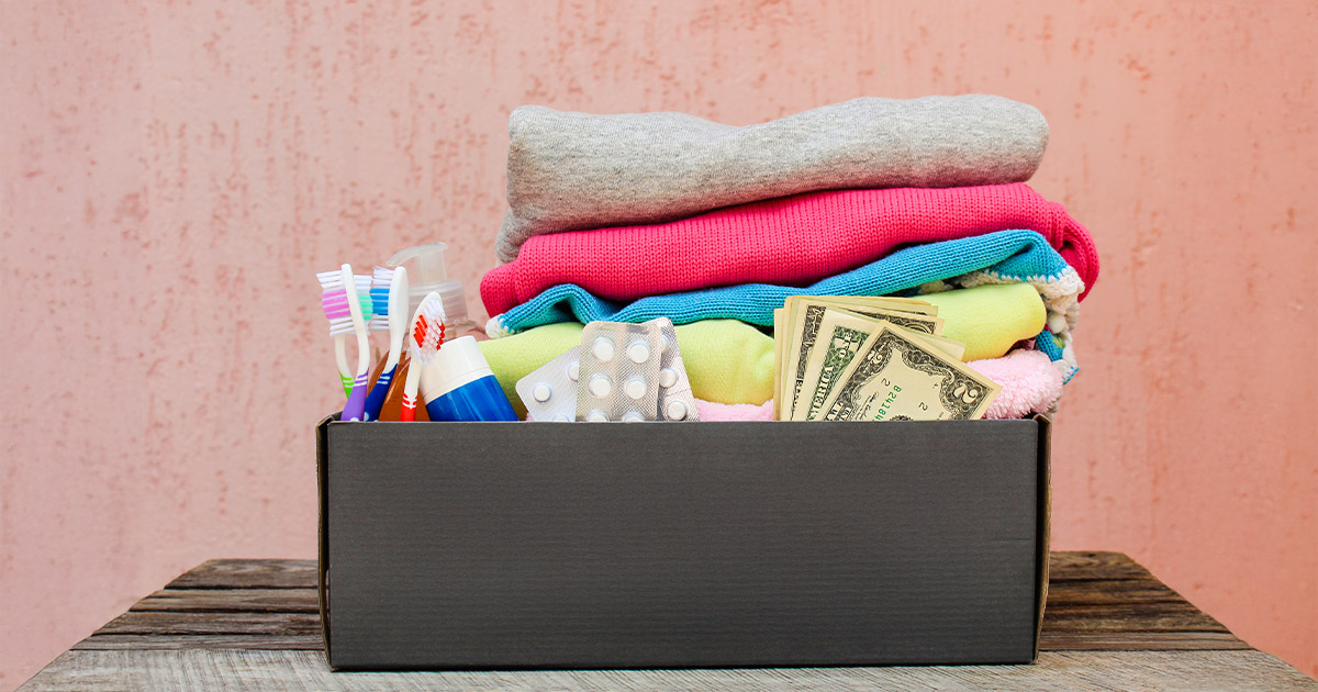 A small box of essential items for a long distance move including medicine, cash, toothbrushes, and clothes. 