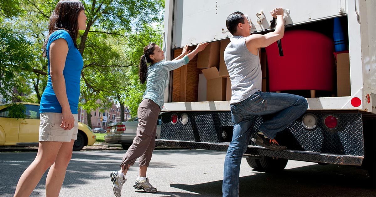 A family of three engages in DIY moving by packing their own rental truck. 