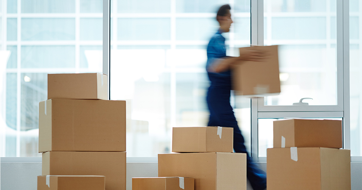 A man walks behind several stack of boxes in preparation for moving day.