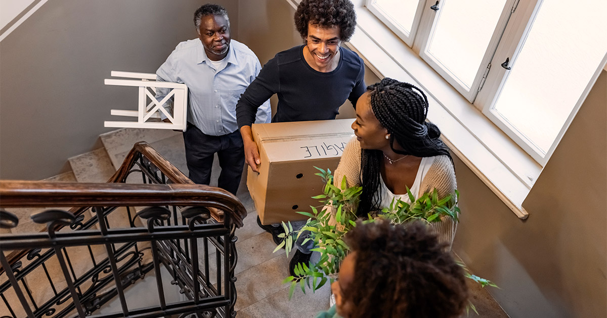 A family of four carries items and boxes up the stairs to their new high rise apartment.