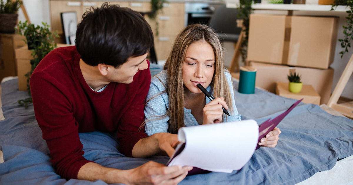 A couple reviews their long distance moving quote options for full service movers. They are surrounded by moving boxes and packing supplies. 