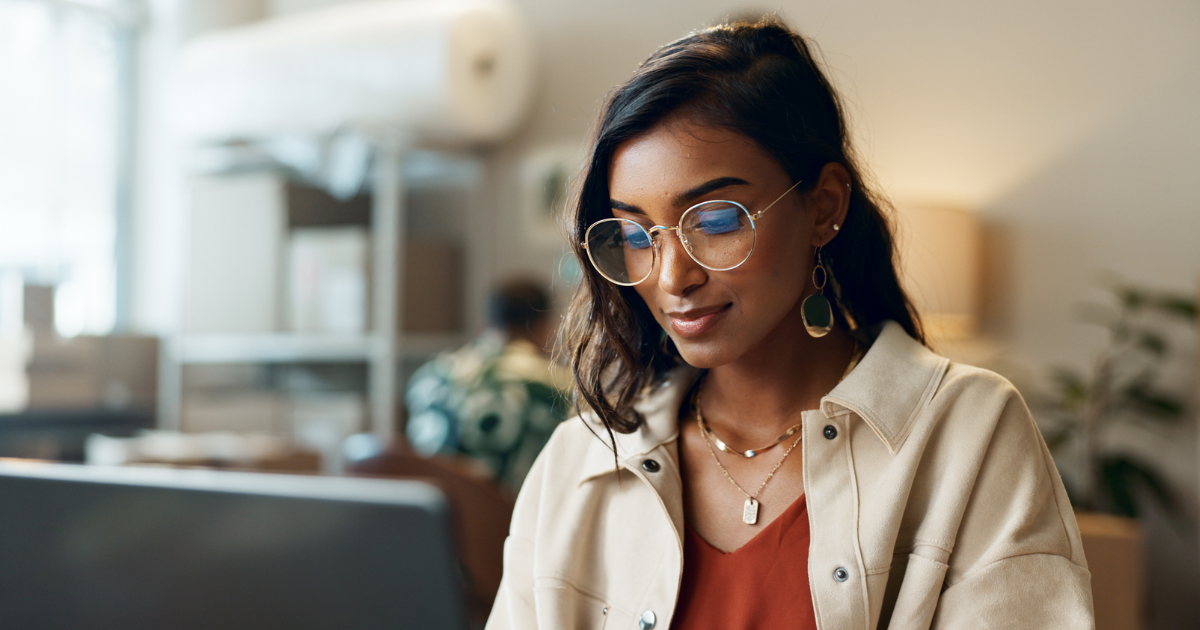 A woman sits at a table in her home. She is looking up reviews for her long distance move, and which long distance moving company she should select.