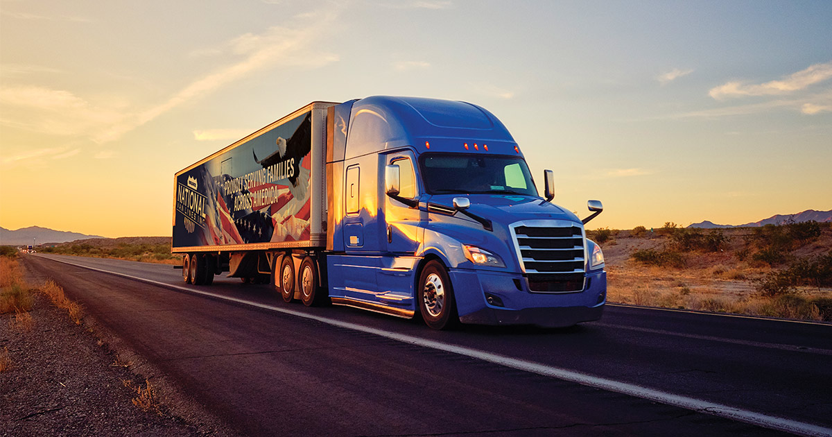 A National Van Lines truck, on the road at sunset, in the middle of a long distance move. 