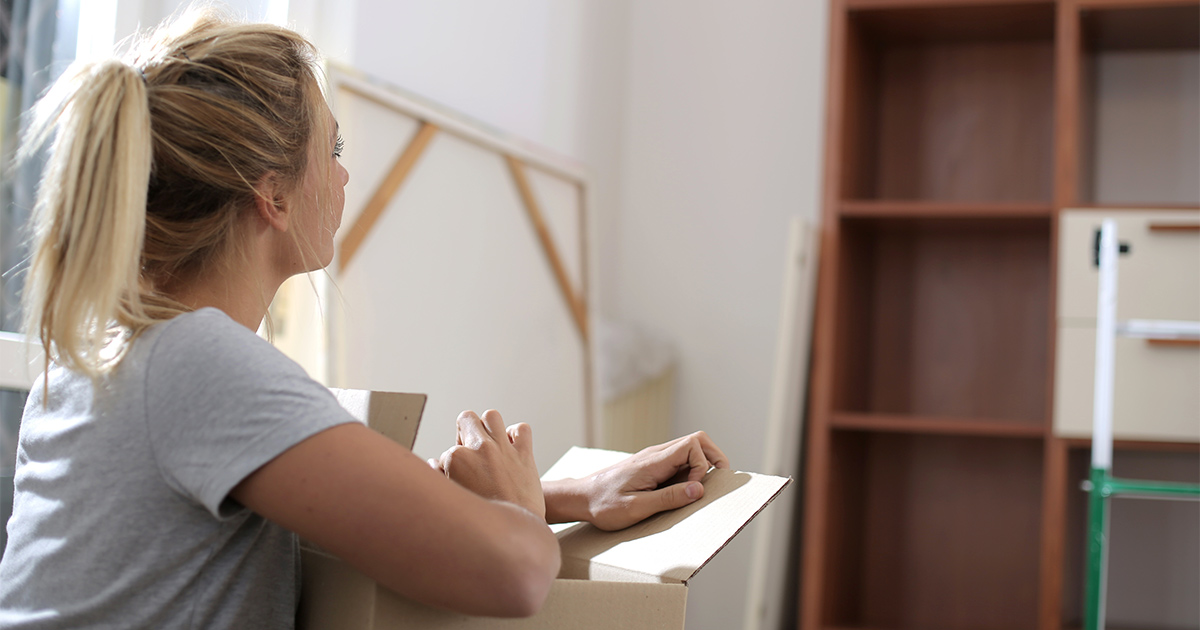 A woman packs her items for an upcoming long distance move while coping with moving stress. She is reflecting on the memories she made in her previous home. 