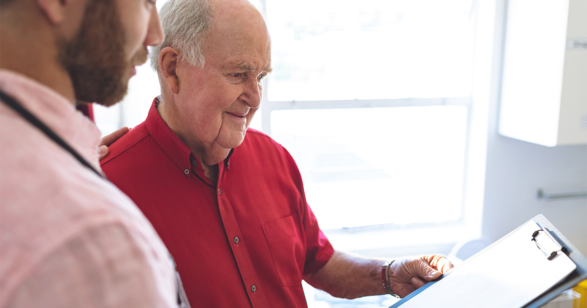 A senior and his family member review details for an upcoming long distance move on a clipboard. 