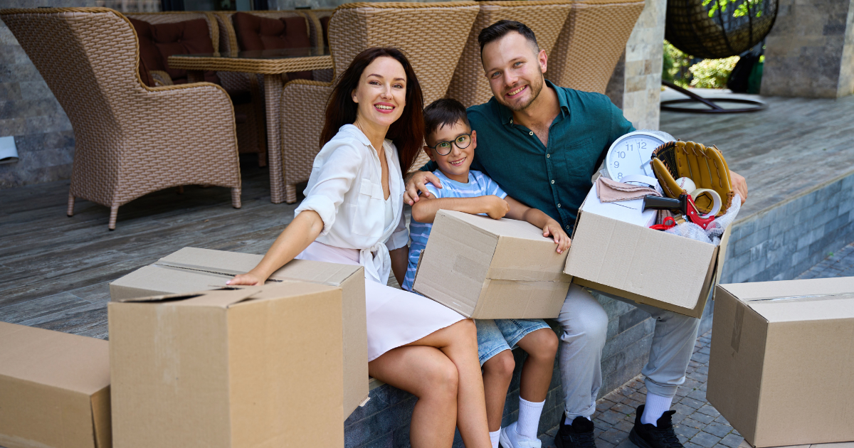 Parents and their child sit amongst moving boxes on the deck of their South Florida home. They are using a South Florida moving company to complete a long distance move.