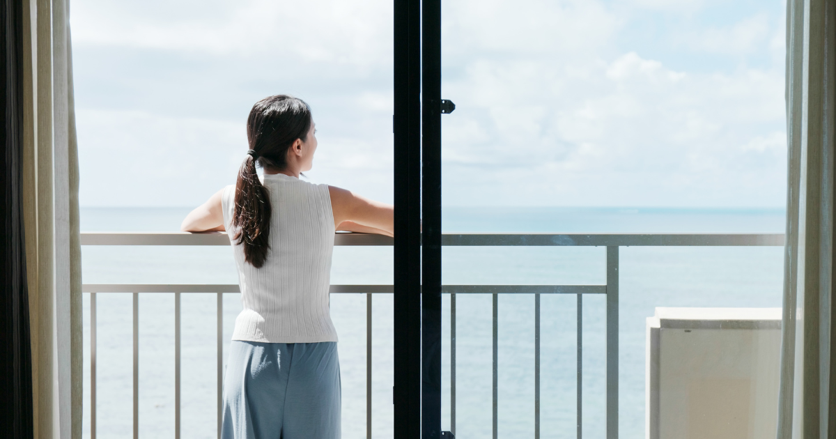 A woman looks out of the balcony of her new South Florida condo. She has just moved long distance.