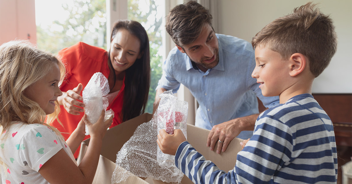A family of four packs their belongings into moving boxes for an emergency move. The mother just got a new job across the country.