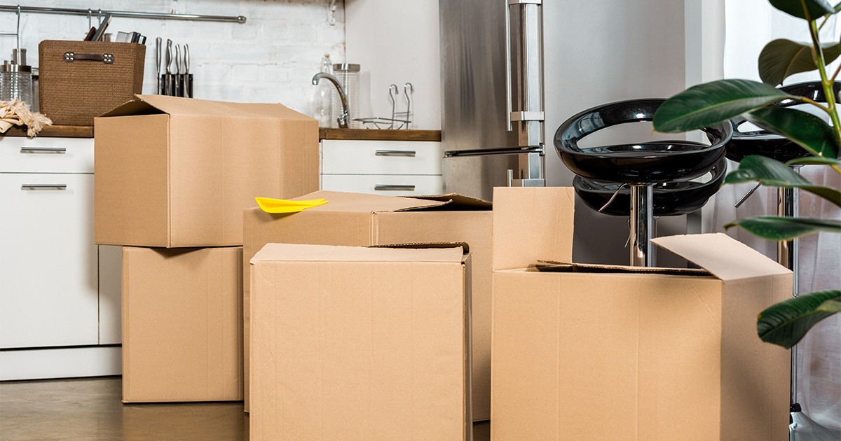 Moving boxes sit in a kitchen in preparation for a cross country move. The person moving has decided to use a full-service moving company for convenience.