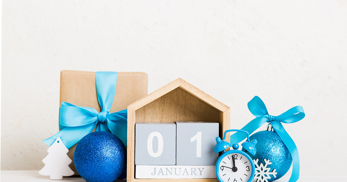 Various decorative blue and white holiday objects sit around a small block calendar. The calendar reads "January 01".